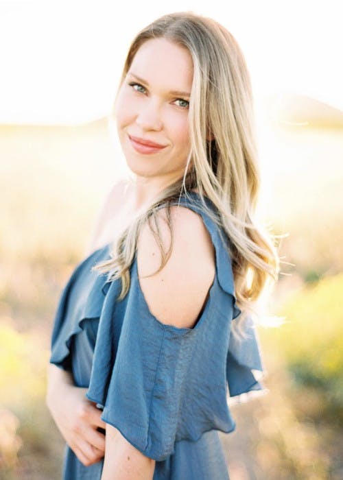 Sunlit portrait headshot of photographer Rennai Hoefer wearing a blue ruffled shirt. 