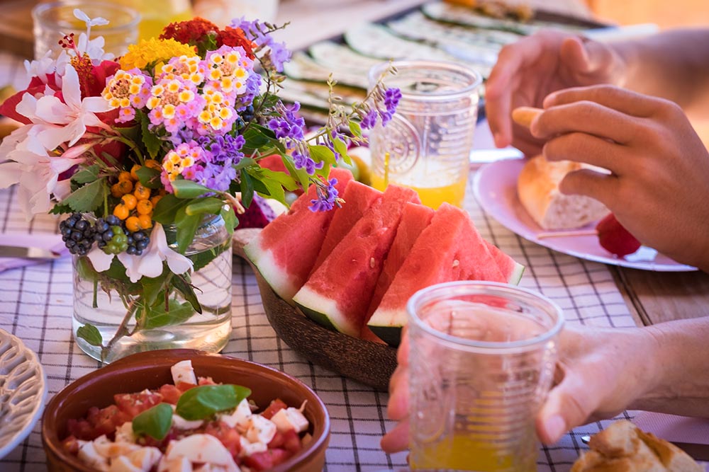 Sunny brunch table setting with watermelon, juice and flowers.