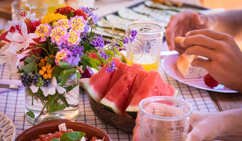Sunny brunch table setting with watermelon, juice and flowers.