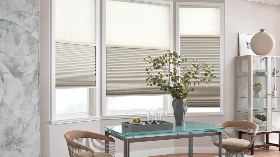 A dining room table in front of a window with Premium Light Filtering Cellular Shades from Blinds.com.