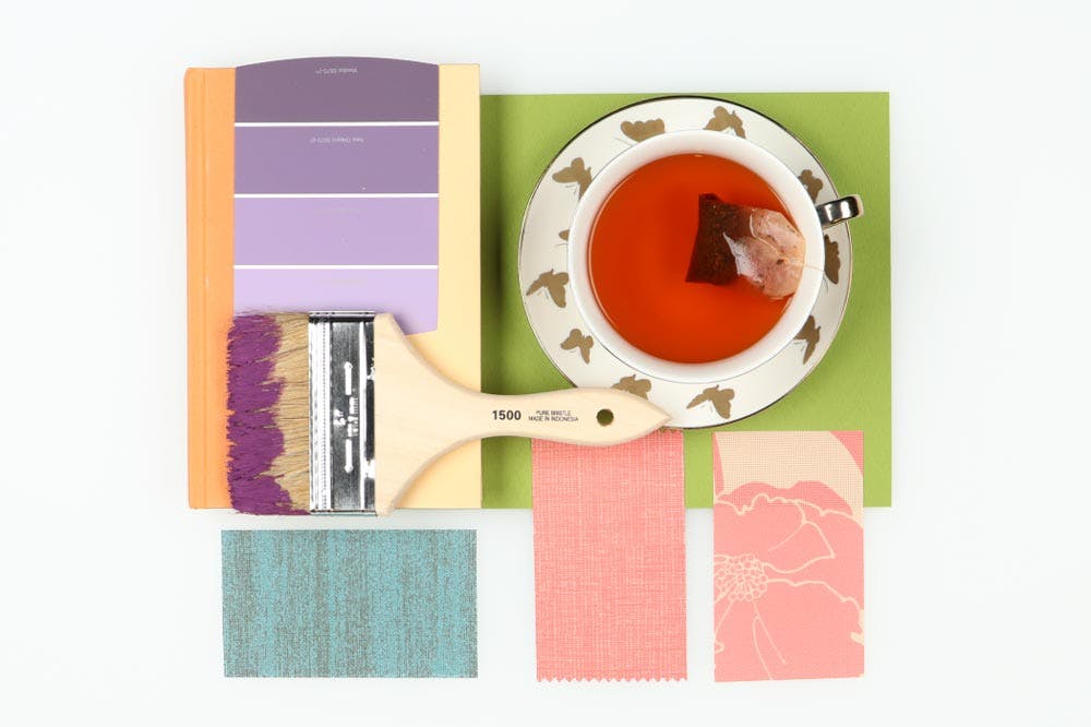 colorful flatlay with teacup, solar shade samples and paint brush.