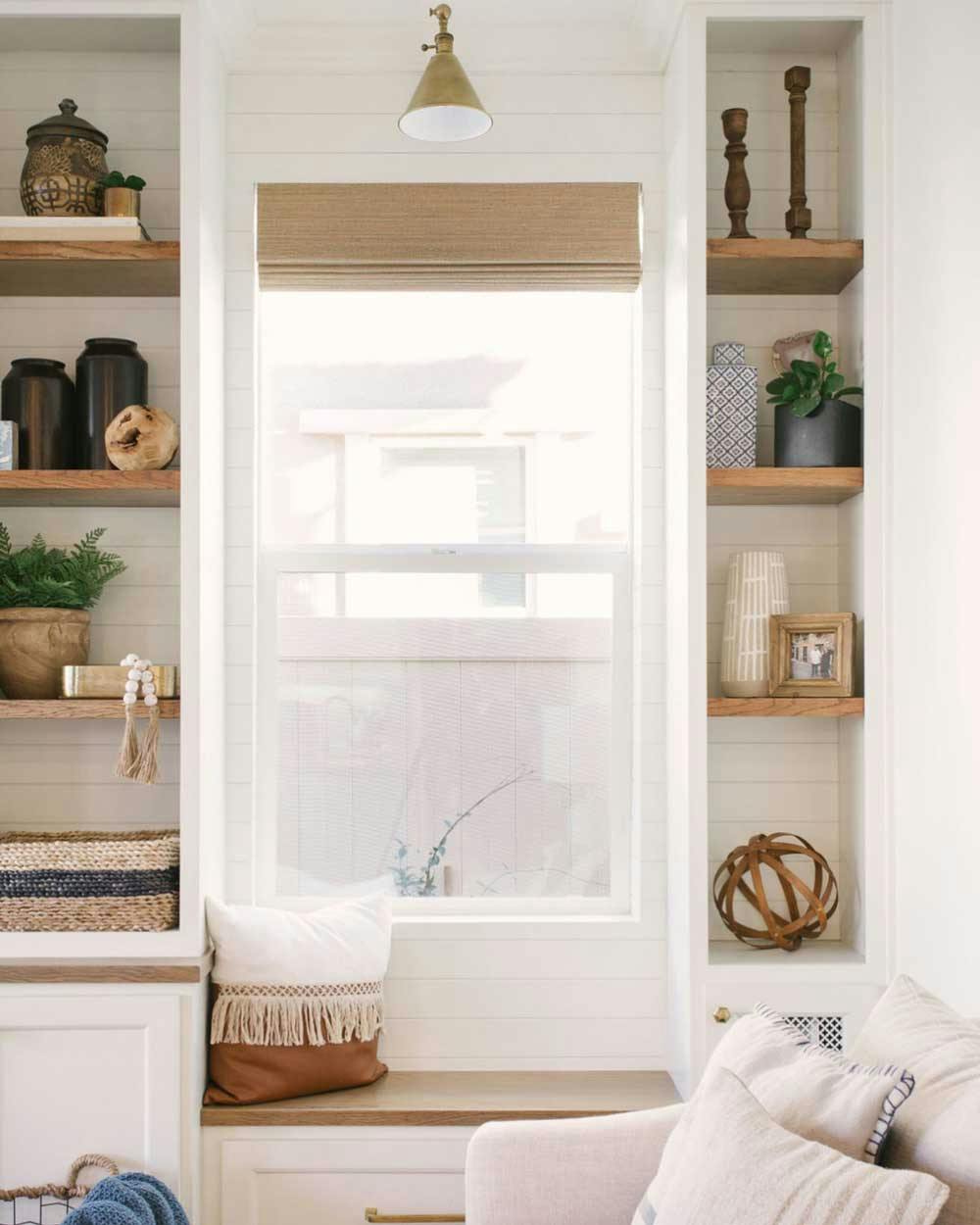small window seat with bookshelves and woven wood shades