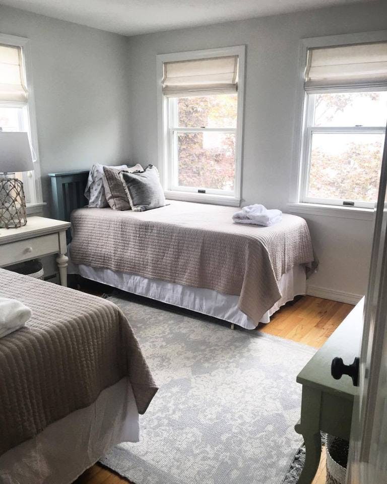 bedroom with two twin beds and white linen roman blinds on windows
