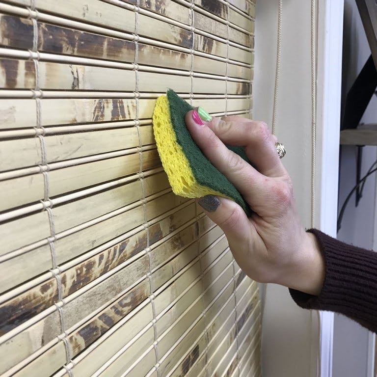 cleaning a woven wood shade with a sponge