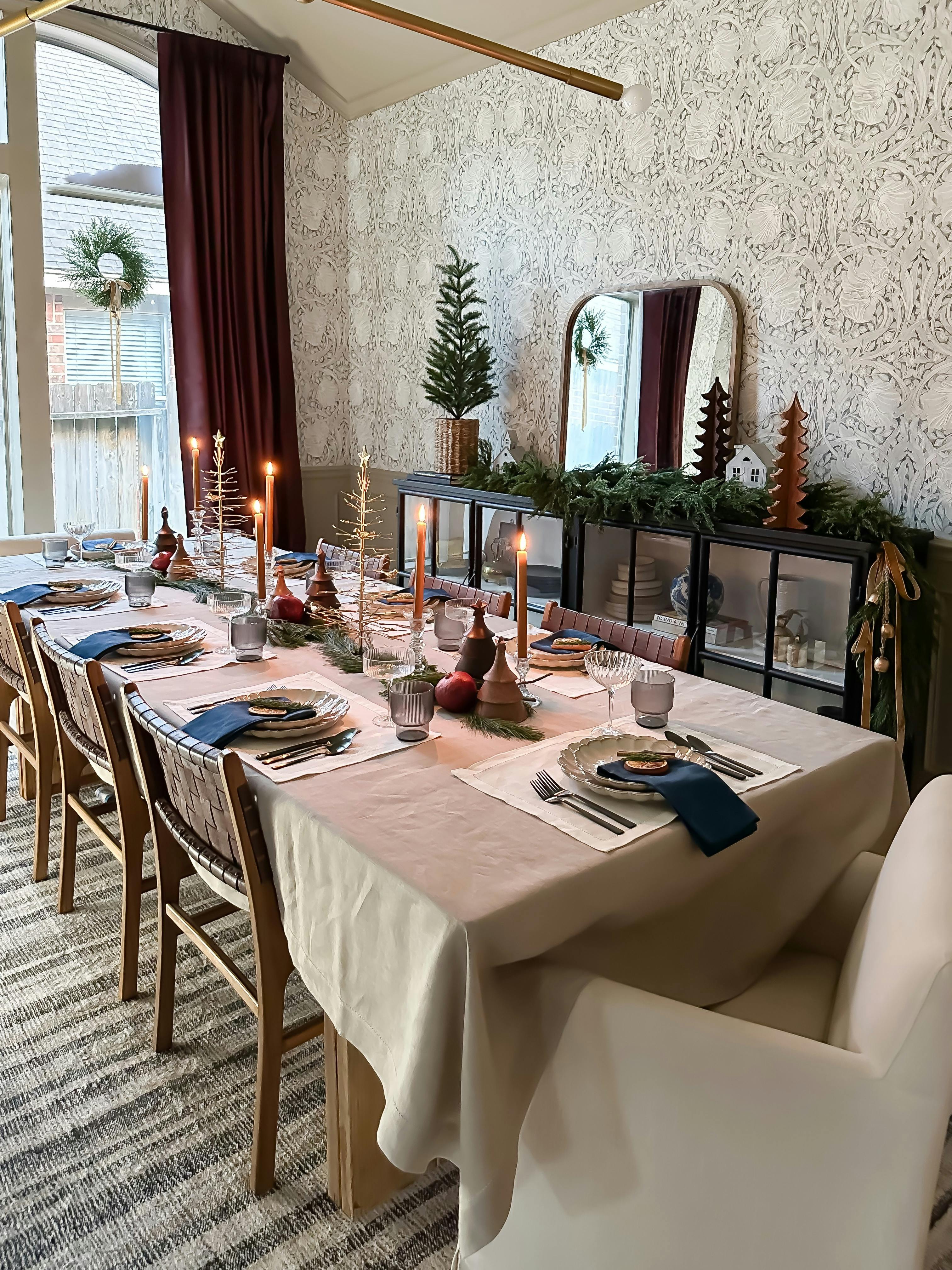 a dining table decorated for the holidays with dark Burgundy drapery