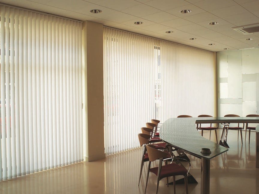 Large room with table and chairs featuring fabric vertical blinds.
