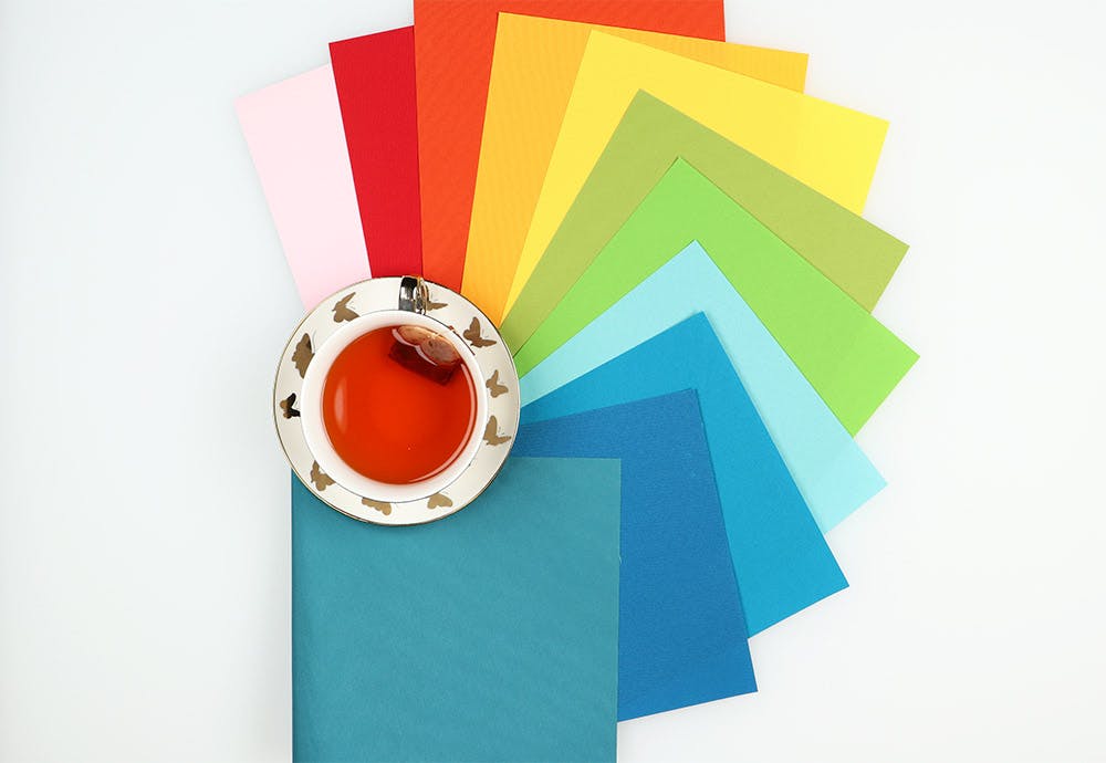 vinyl fabric samples in rainbow order around a white and gold tea cup.