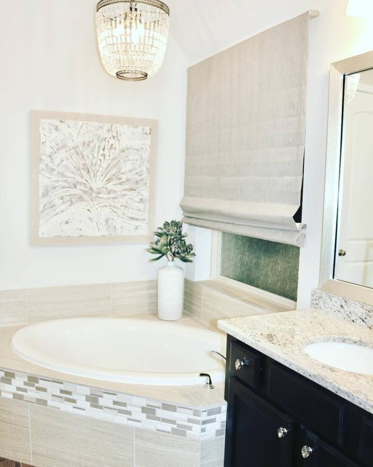 corner garden tub with large window covered with flat beige roman shade