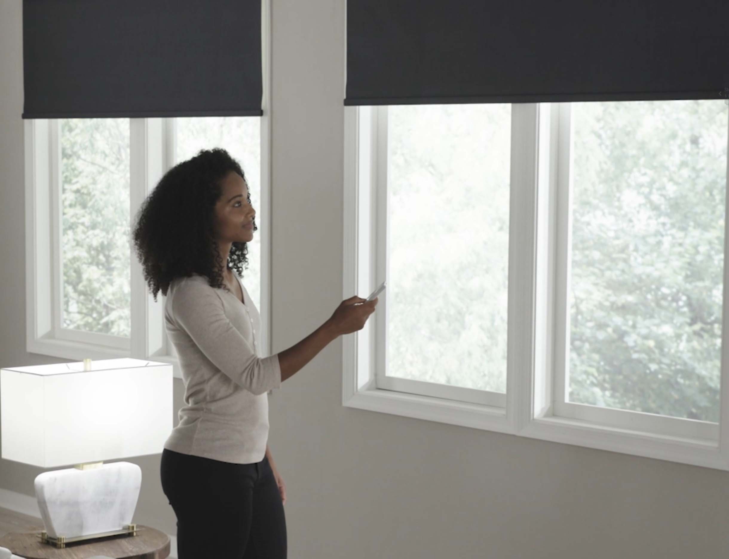 a woman operating her motorized blackout roller shades