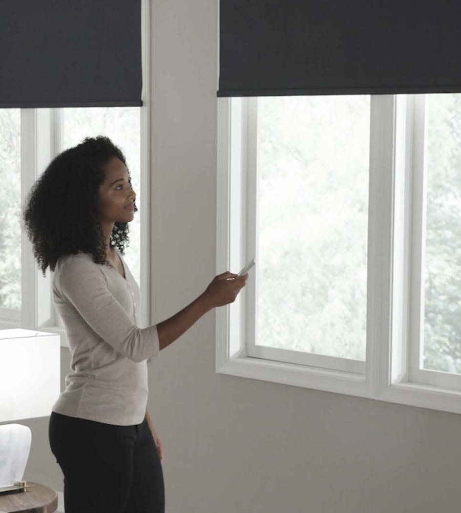 a woman operating her motorized blackout roller shades