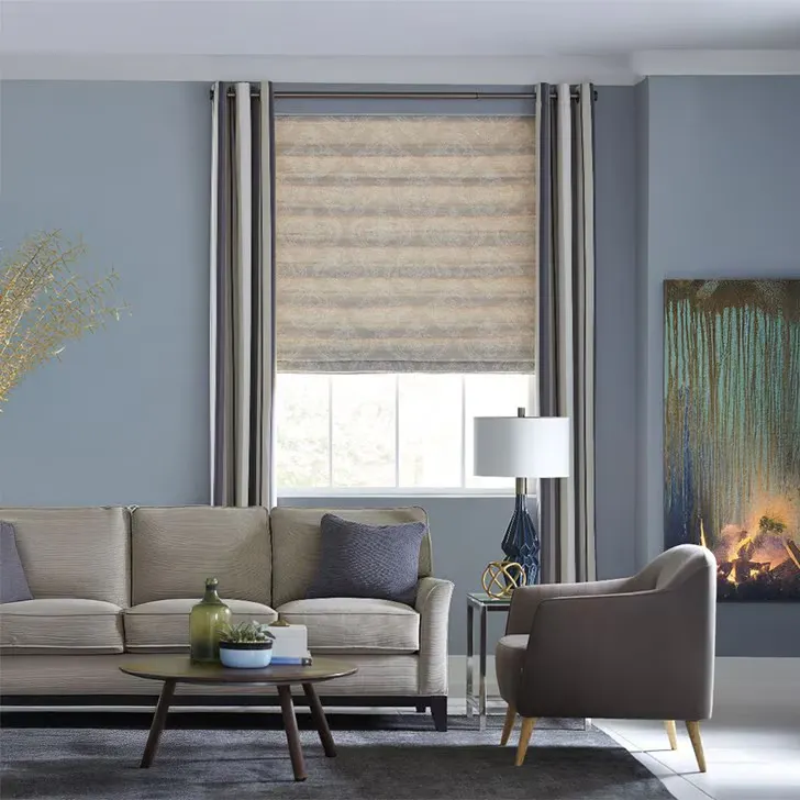 Blinds.com Light Filtering Roman Shades in a neutral fabric, softly filtering natural light in a modern living room with gray furniture and blue walls.