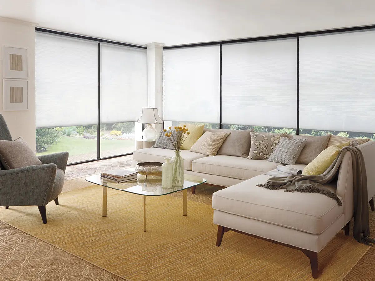 Expansive living room with cellular shades and yellow and grey accents.
