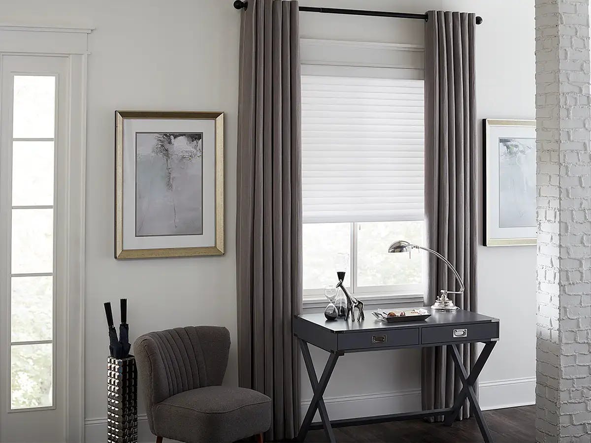 An entrance way with a dark desk and long grey curtains.