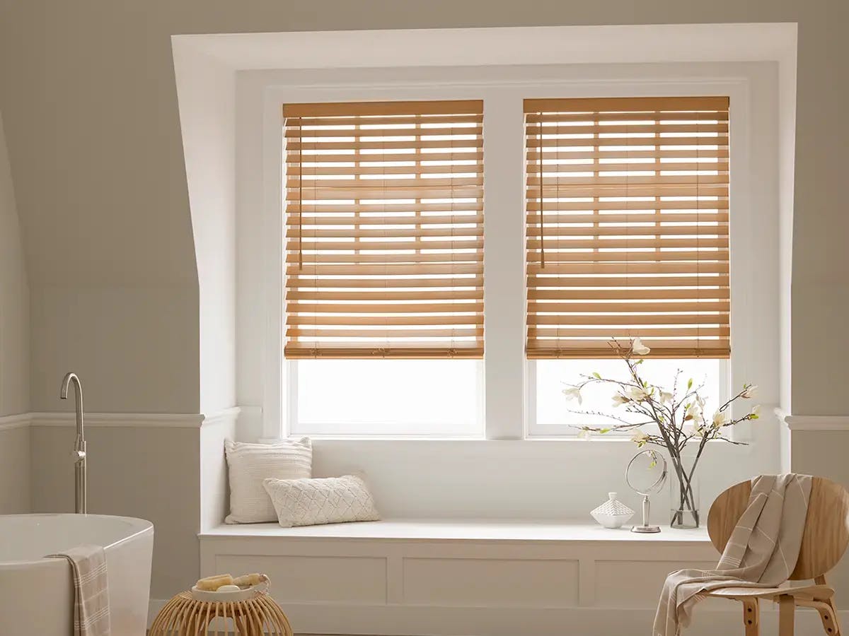 Bathroom with wooden blinds, a bathtub, and neutral decor.