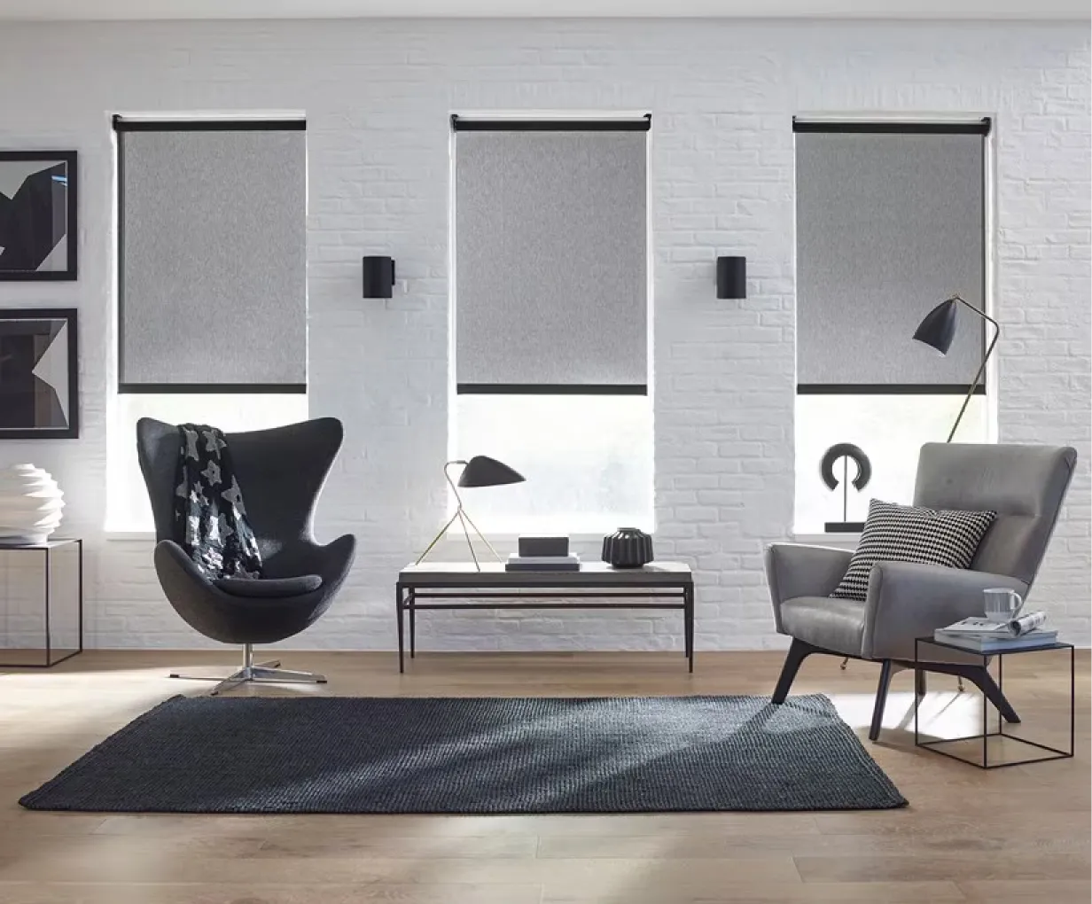 A modern sitting area with a gray and black color scheme. The windows have gray solar roller shades pulled halfway down.