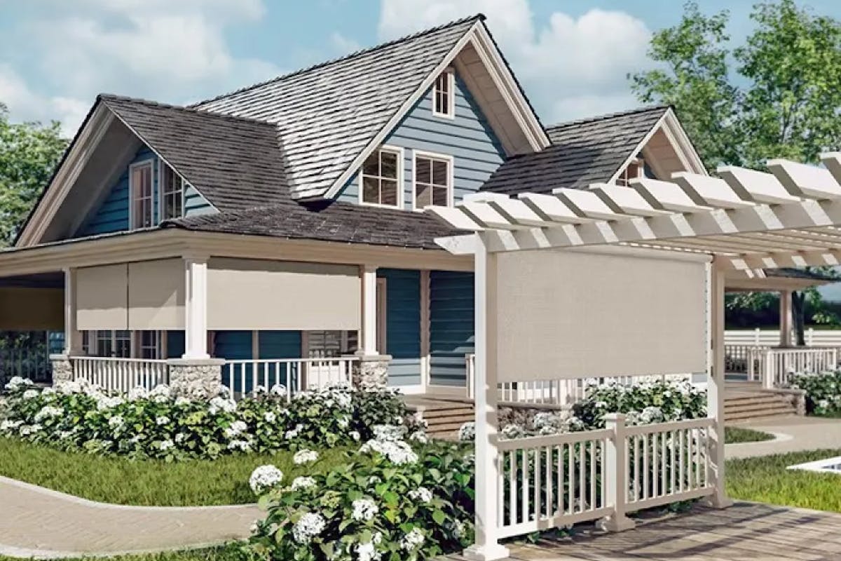 A blue house with white railing and a gray roof. There’s a matching Pergola on the front lawn and light-colored exterior shades hanging from the patio and the pergola.