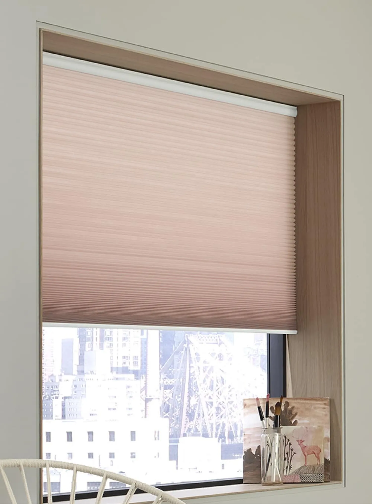 Window with pink, light-filtering cellular shades. There’s small decor on the windowsill.