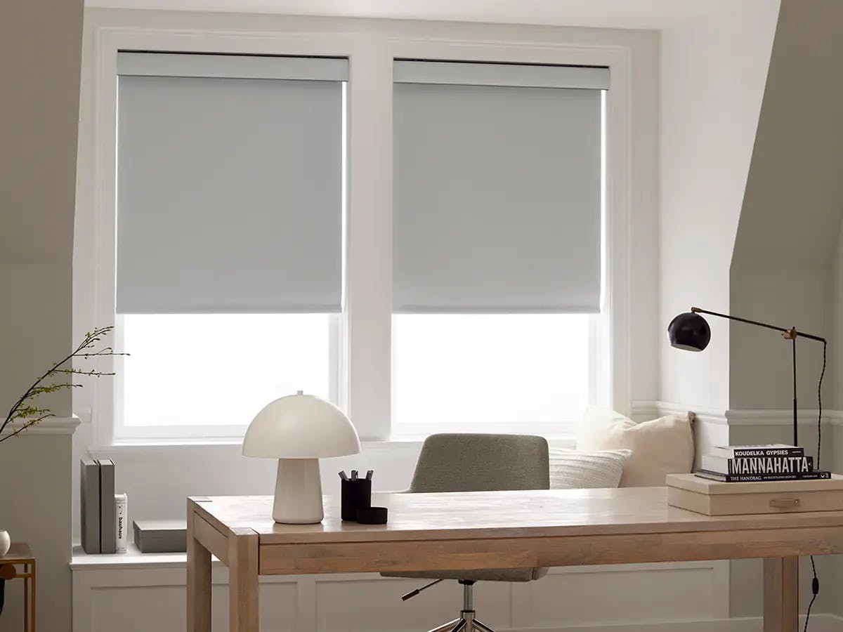 Office space with white roller shades.