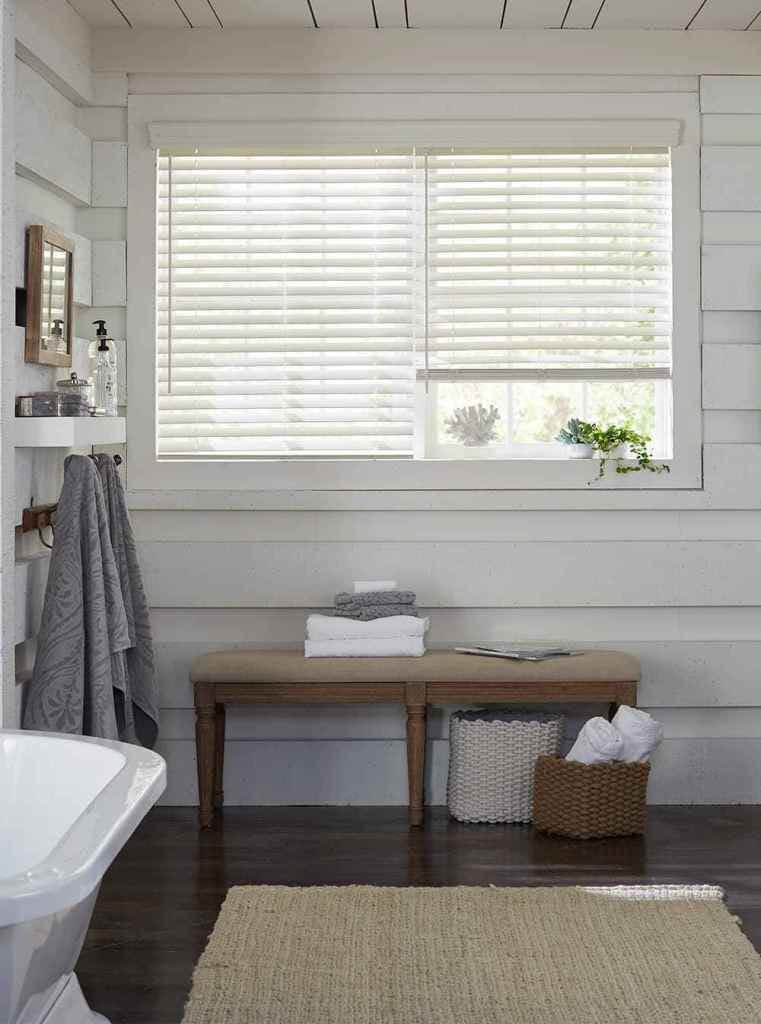 bathroom with wood walls painted white and window with two white wood blinds