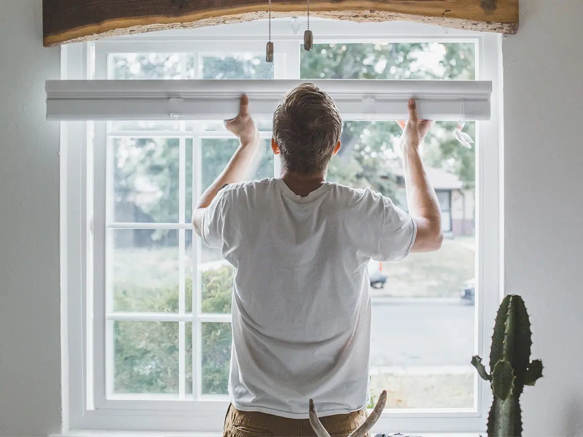 Man installing blinds on a window frame.