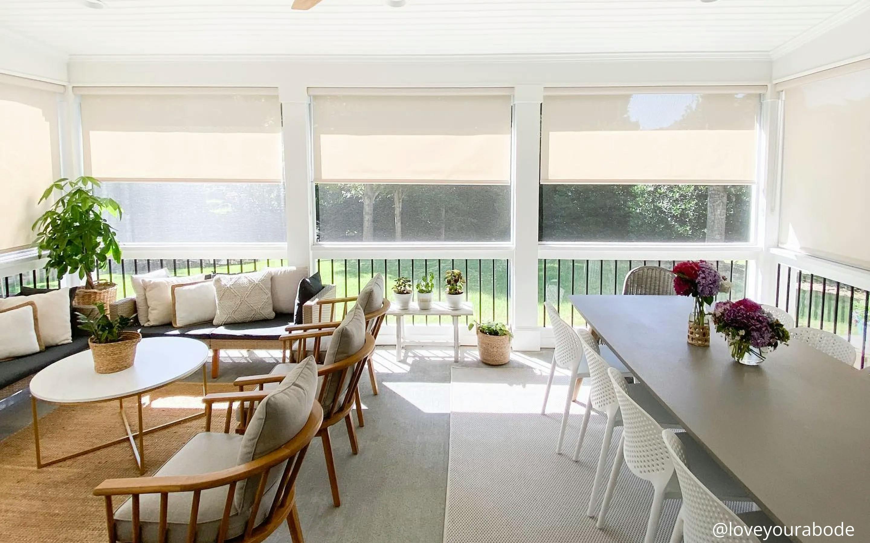 Outdoor patio with a table and chairs. There are neutral-colored outdoor shades all around the railing.