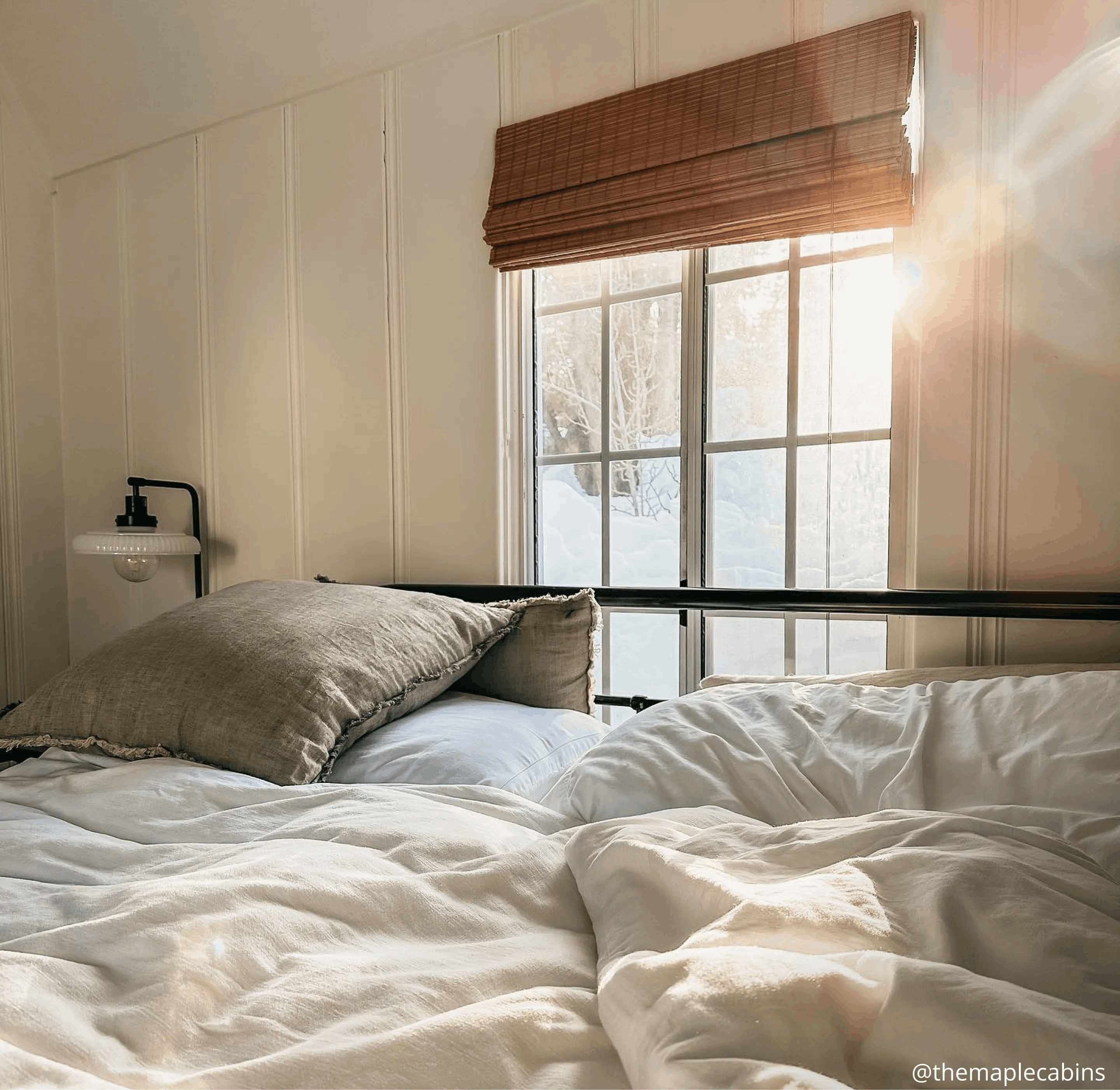 Woven wood shades on a window above the bed.