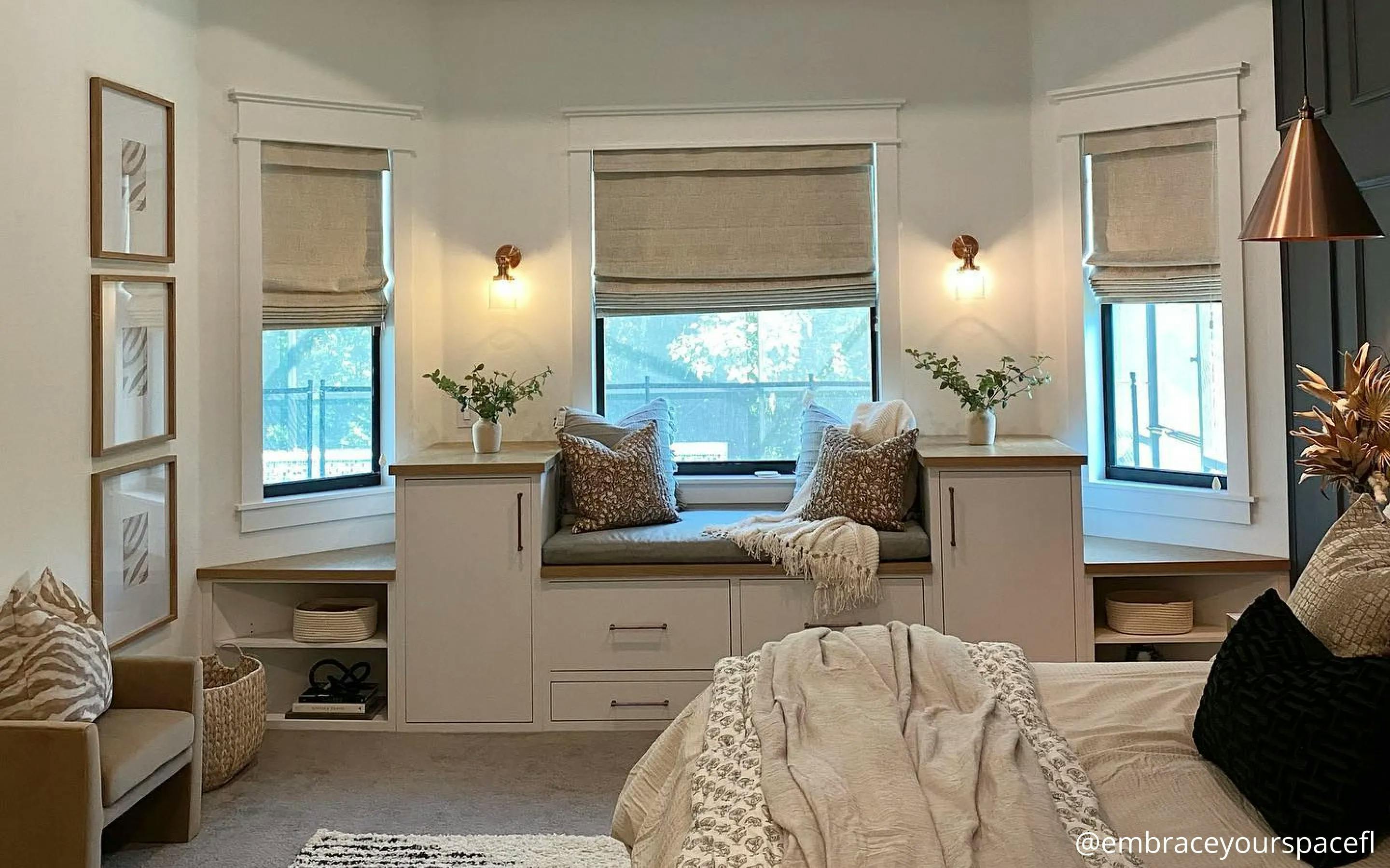 Bedroom with a seating area under the windows. The windows have neutral colored shades.