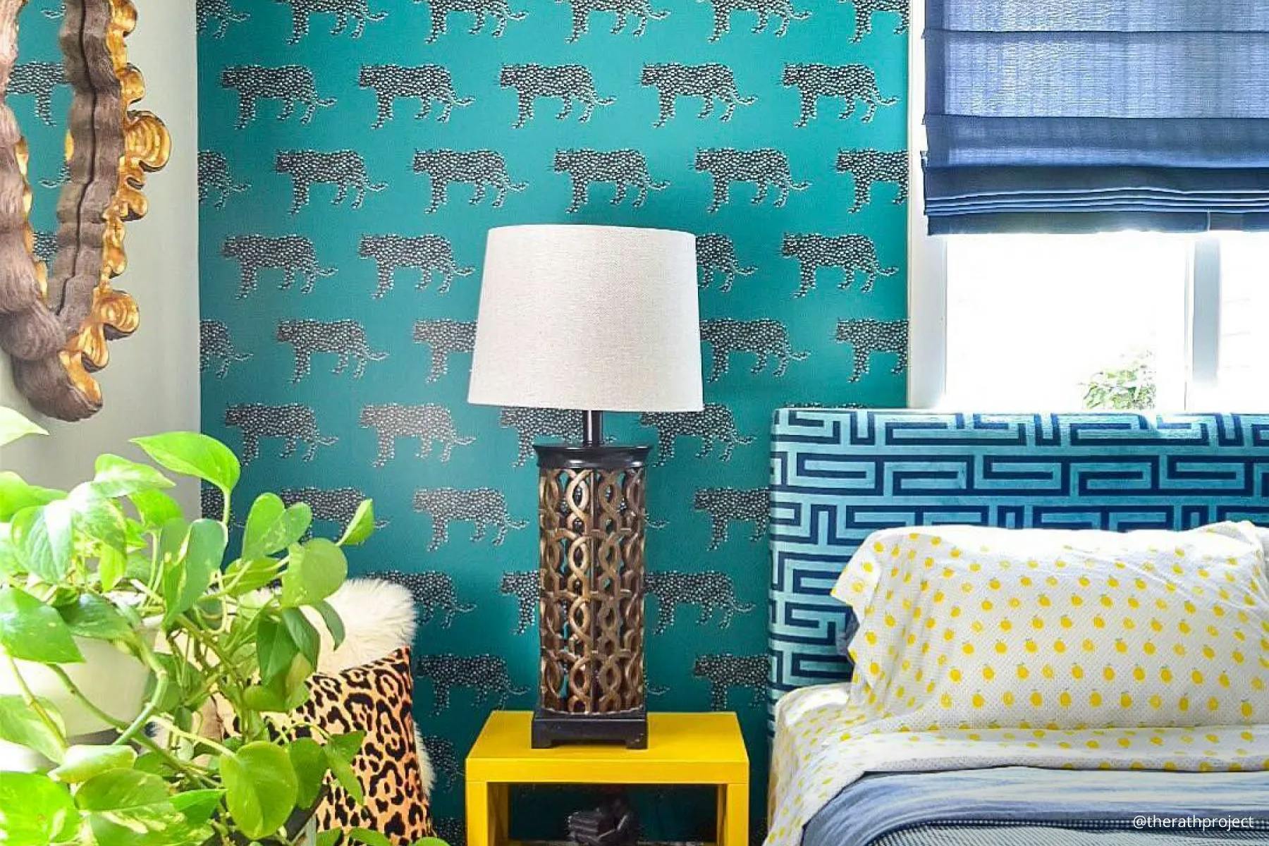 Bedroom with blue tones, patterned wallpaper and decorations and an overall maximalism style. The window is covered in royal blue, light-filtering Roman Shades.