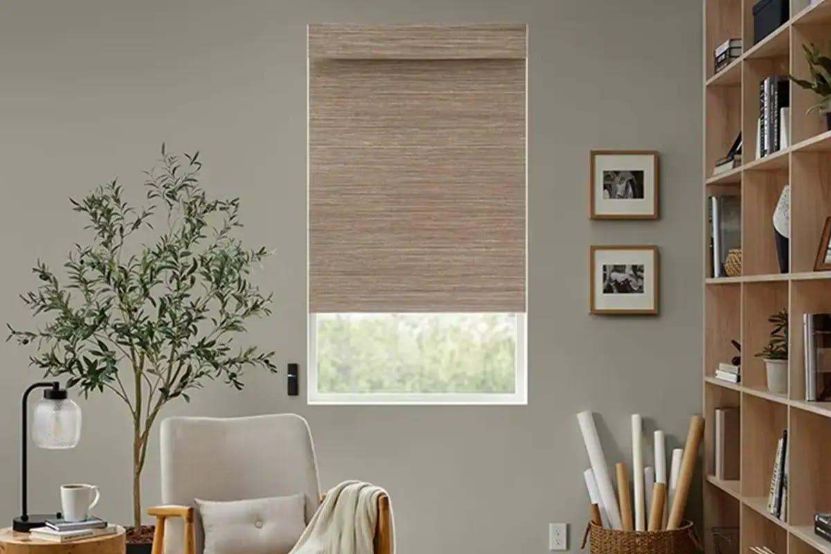 Room with beige woven wood shade partially lowered over a window.