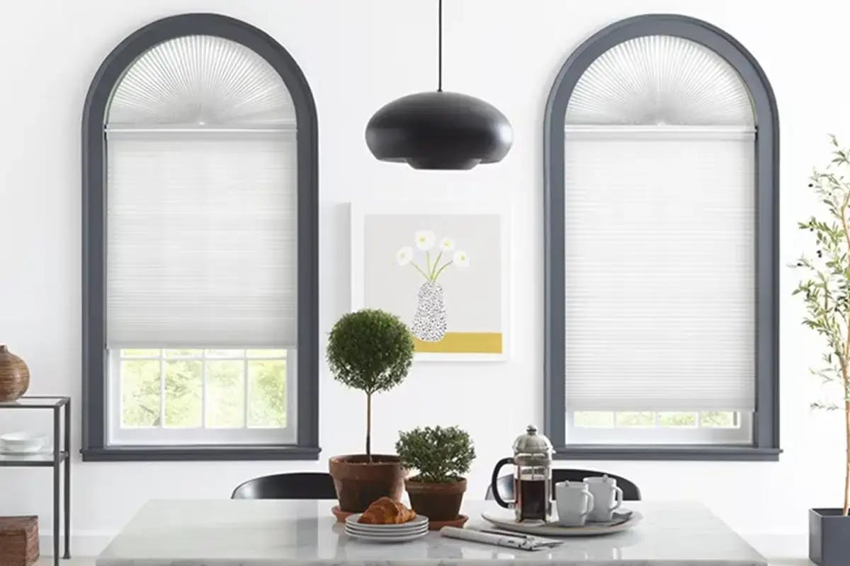 Dining area with two arched windows featuring light gray cellular shades.