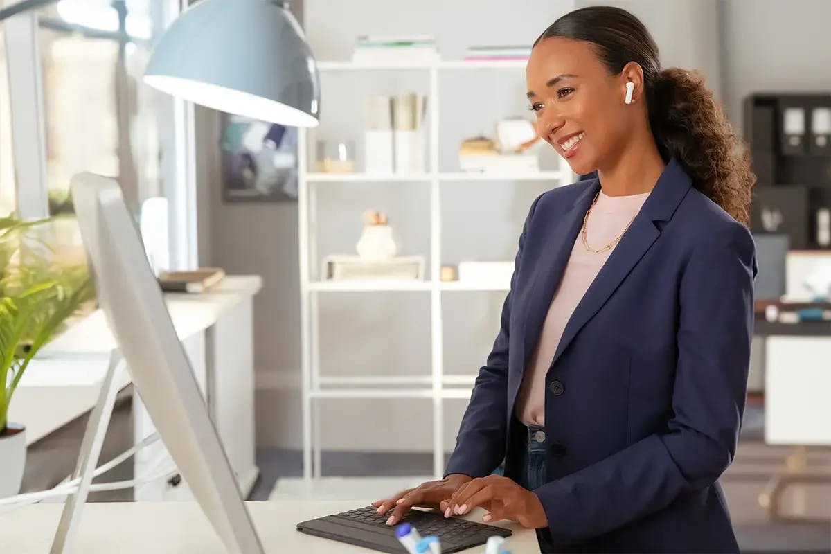 Woman smiling while working at a standing desk computer.