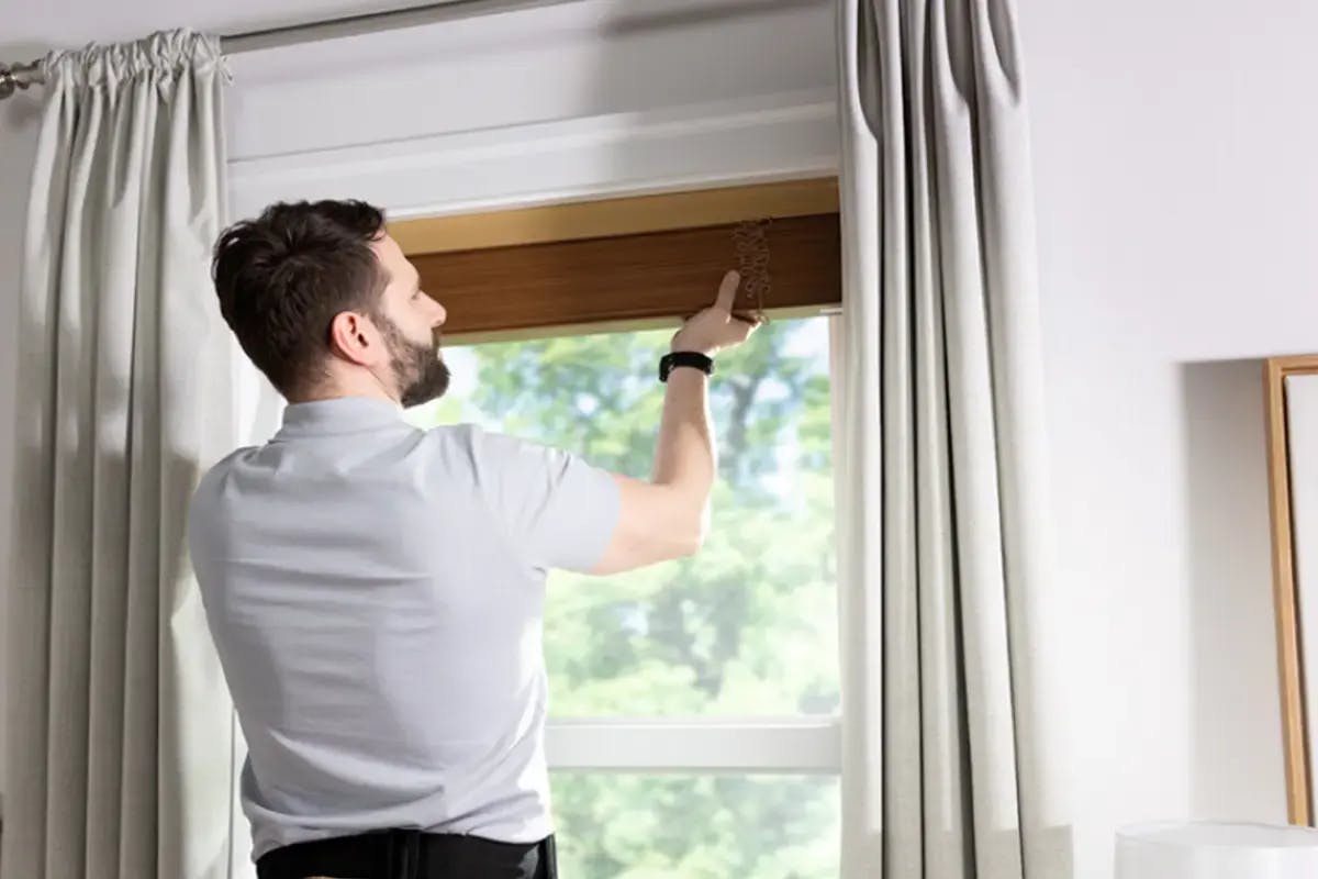 Man measuring window width with a tape measure.