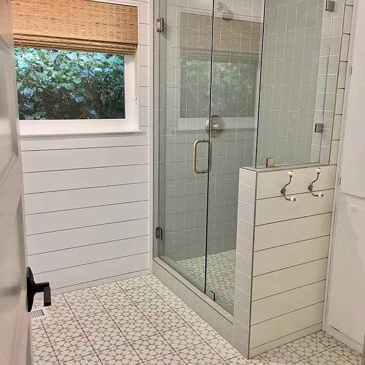 bathroom with patterned tile floor, shiplap walls and woven wood shade over window