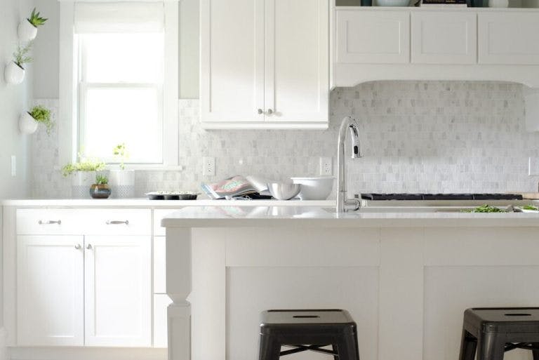 white kitchen with small marble tile backsplash and white roman shades