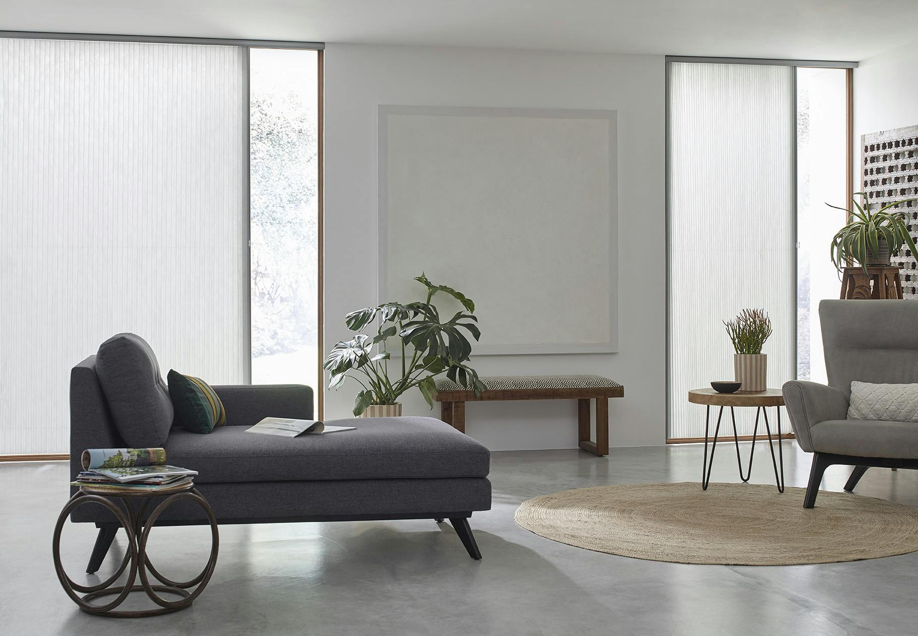 Modern, grey toned living room with two large sliding glass doors covered with white, light filtering vertical cellular shades.
