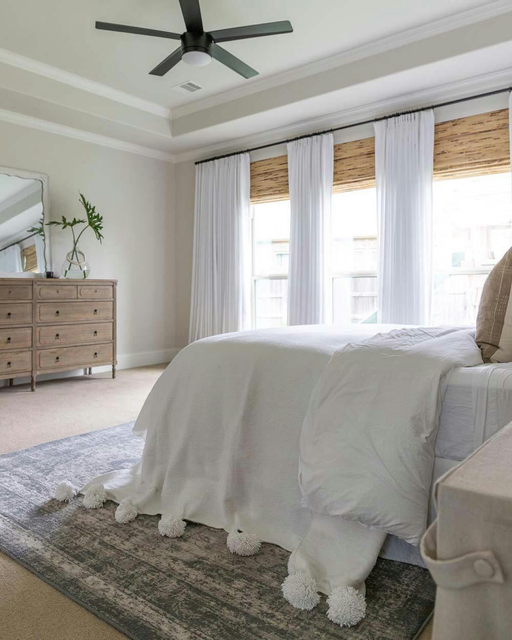 neutral master bedroom with beige walls, white curtains and bamboo blinds