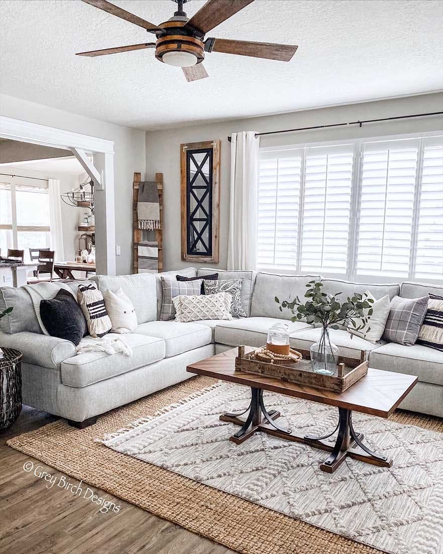 Modern farmhouse living room with grey couch and white plantation shutters.