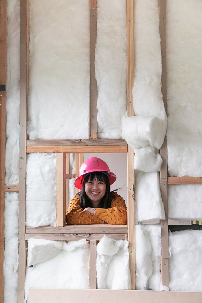 woman looking through framed window with insulation on construction project