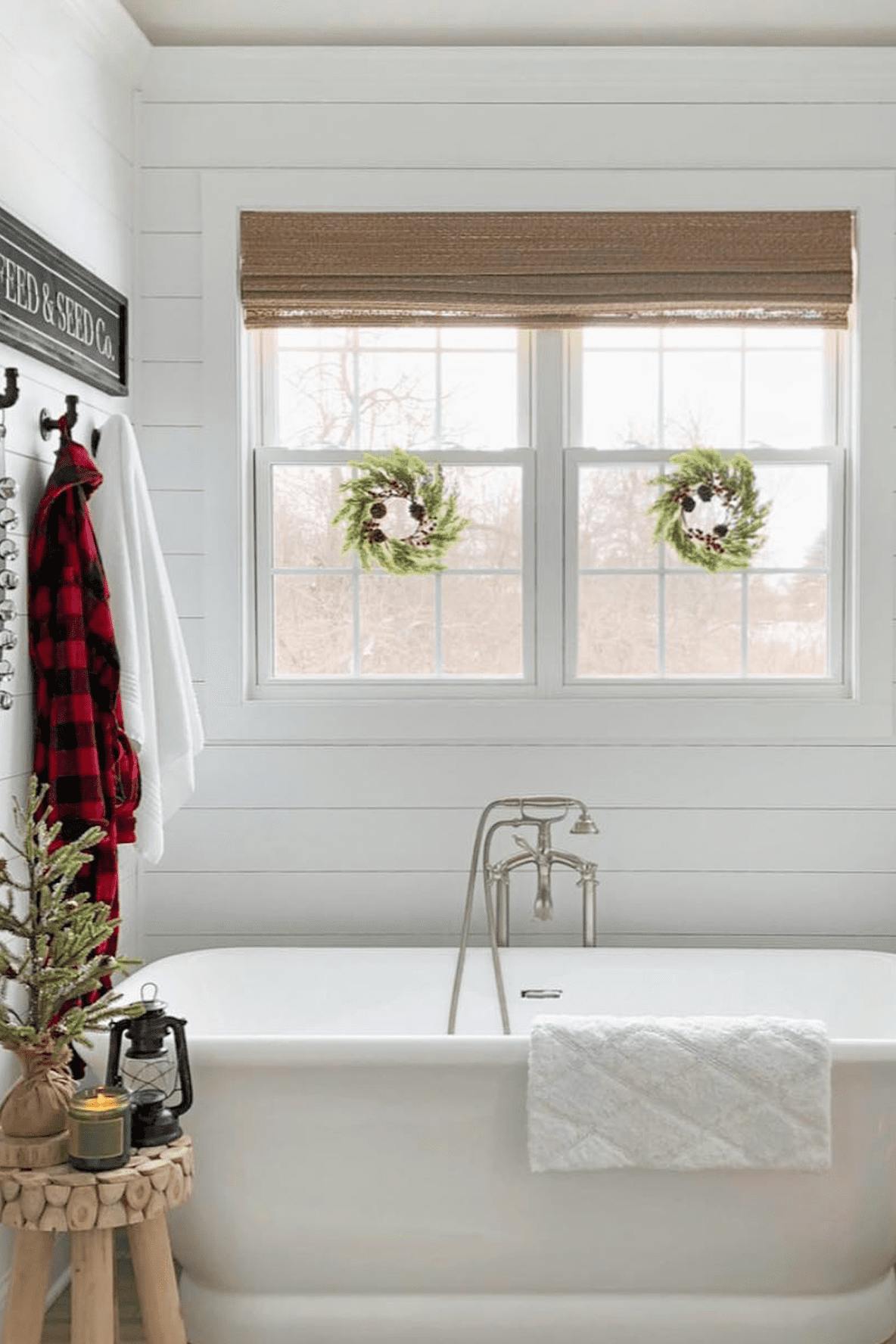 Bathroom window with woven wood shade and two holiday wreaths over the glass.