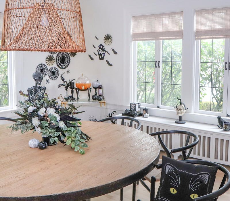 Kitchen decorated for Halloween with small Halloween window display and a pumpkin shaped carafe in the corner.