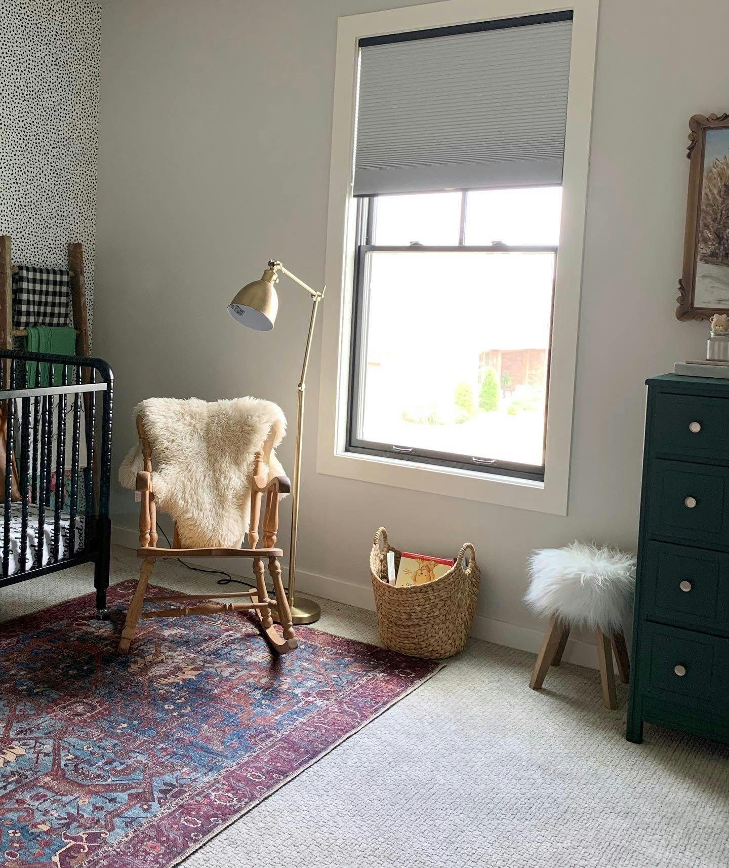 vintage style nursery with wood furniture, turkish rug and grey cellular shades in window