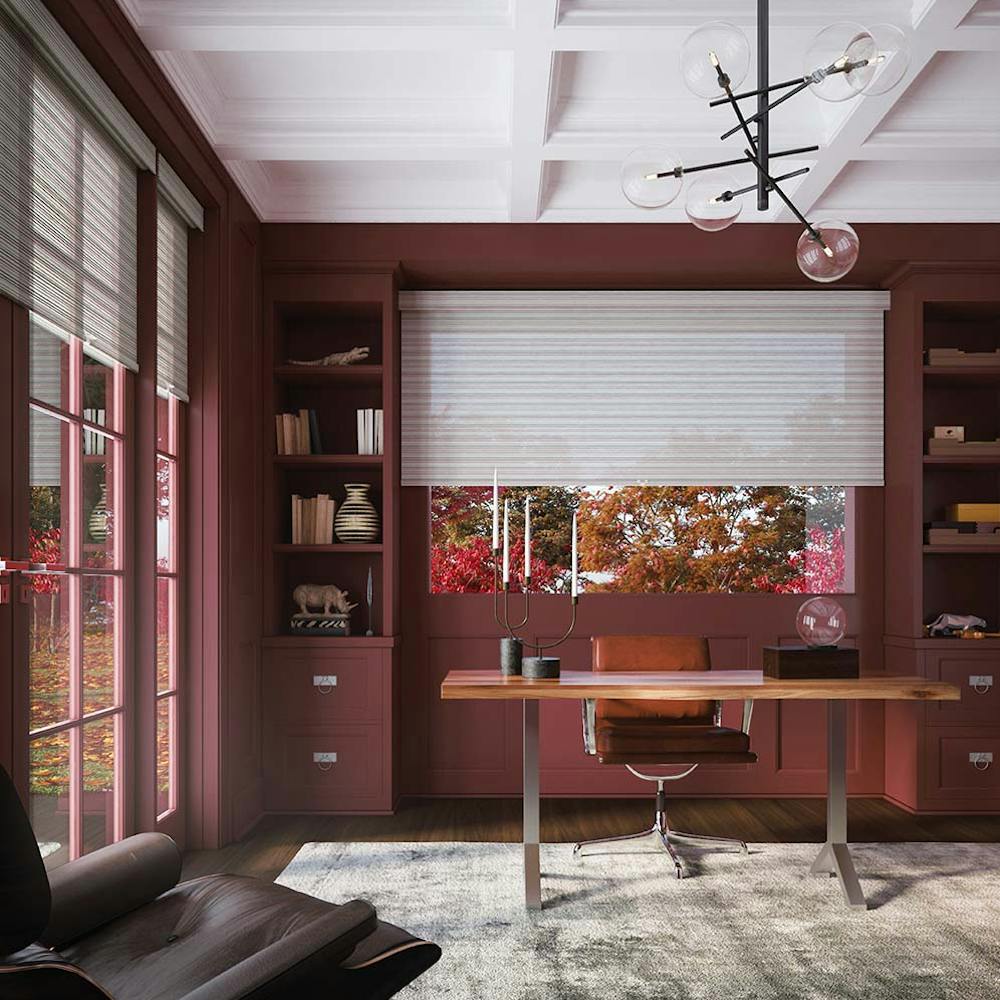 modern office with maroon walls, white roller shades and oak desk.