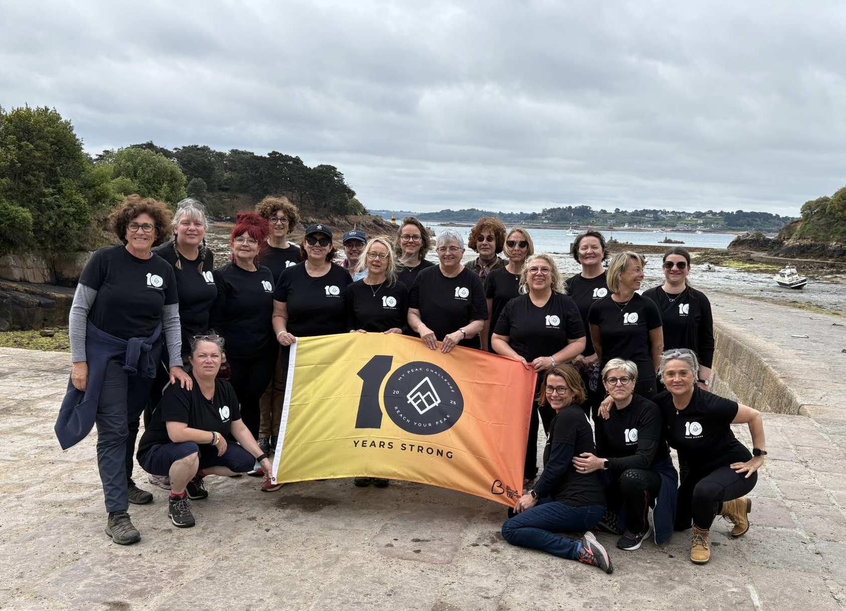 Participants smiling atop a peak, holding an MPC banner.