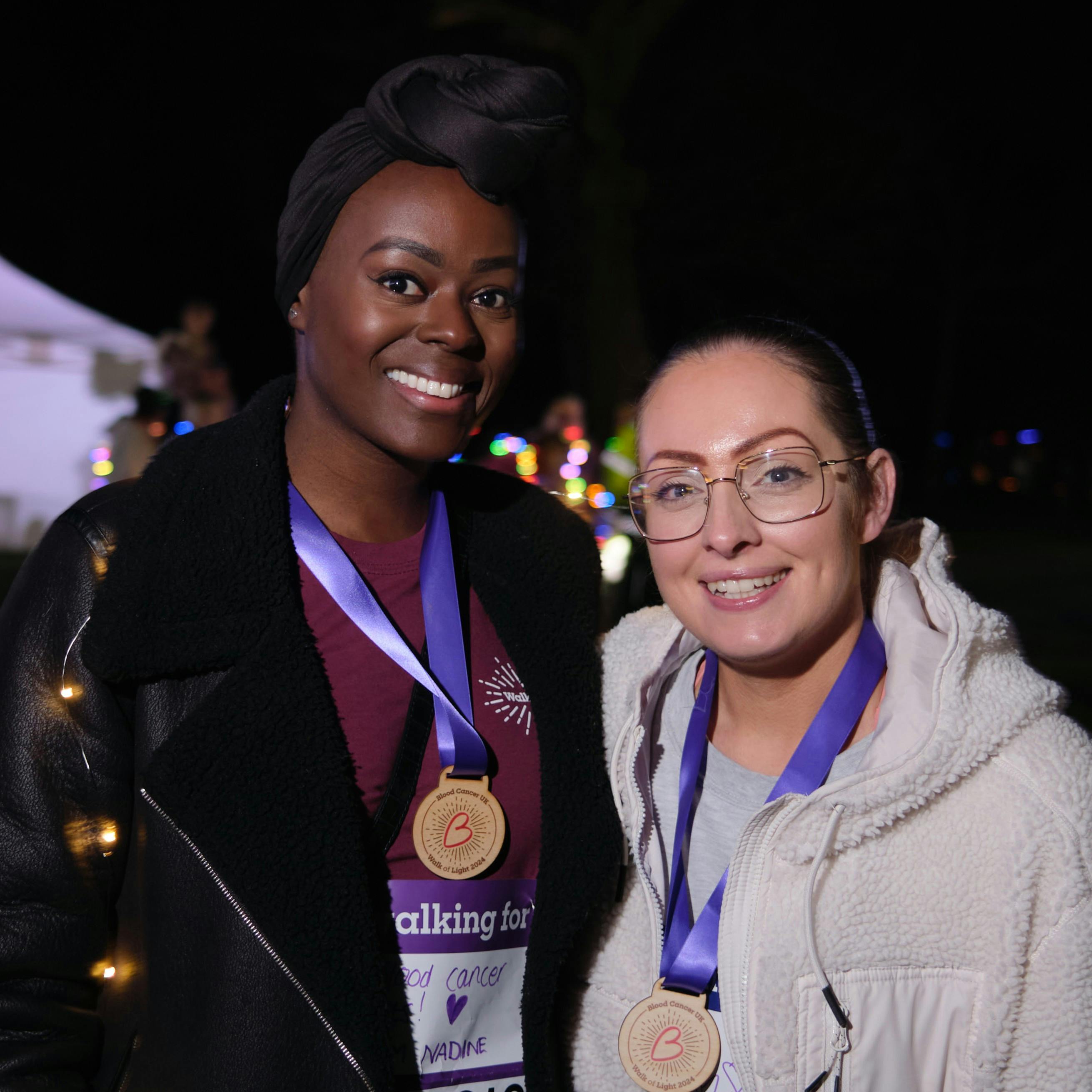 Two adults smiling whilst wearing Blood Cancer UK medals and t-shirts