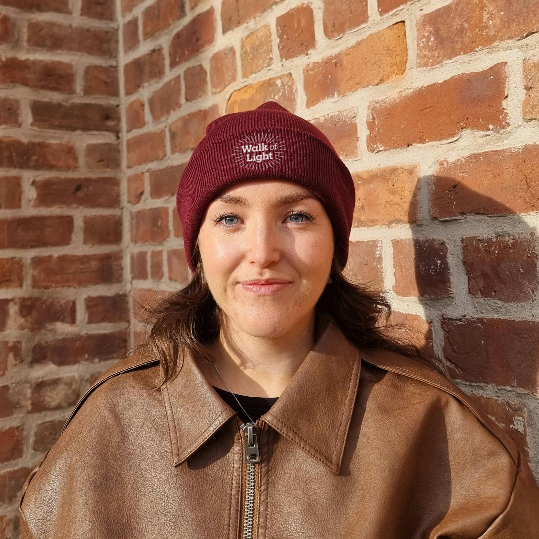 Smiling adult wearing free red Blood Cancer UK beanie