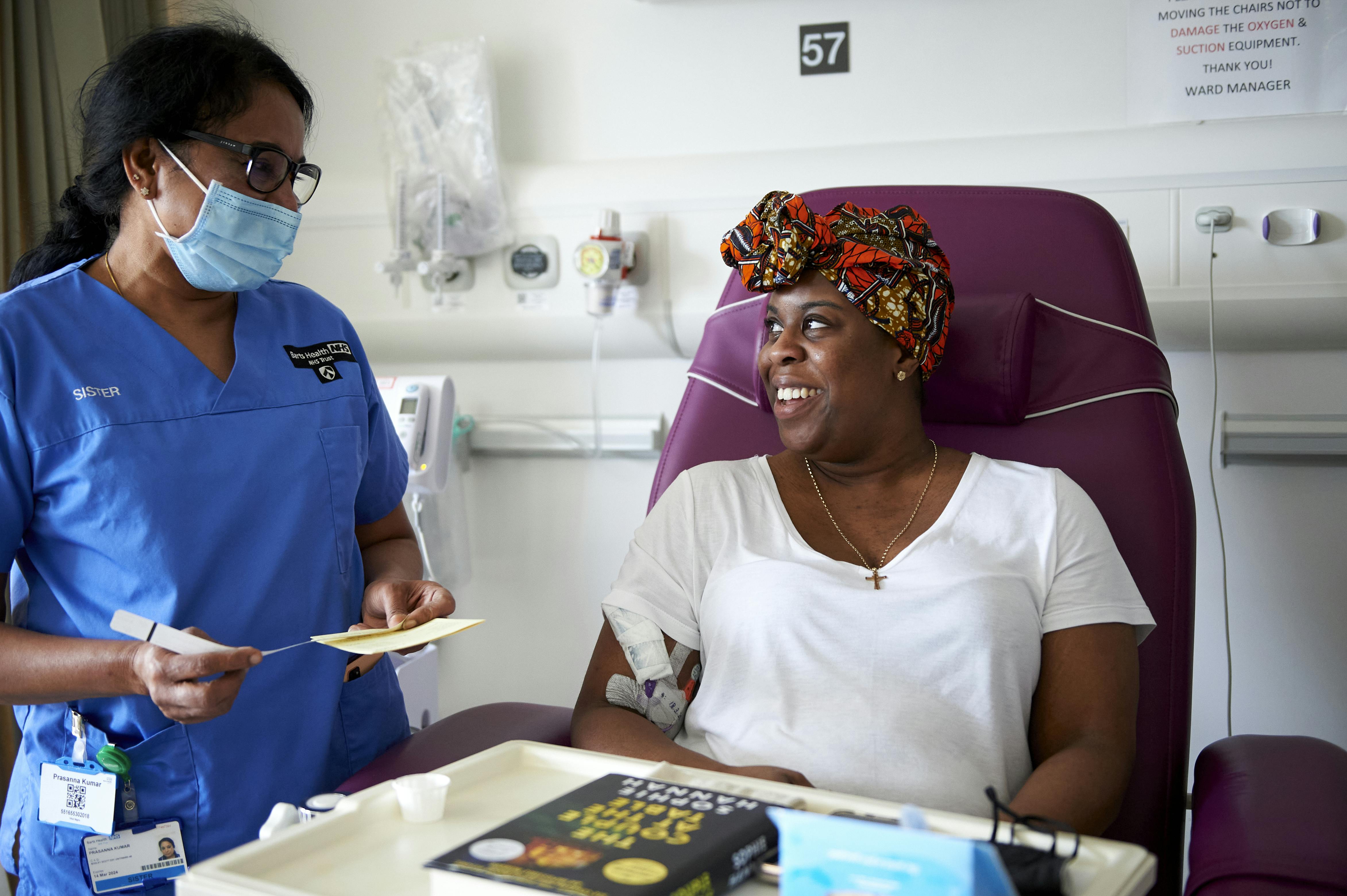 A clinical nurse specialist standing next to a patient in hospital bed wearing her uniform