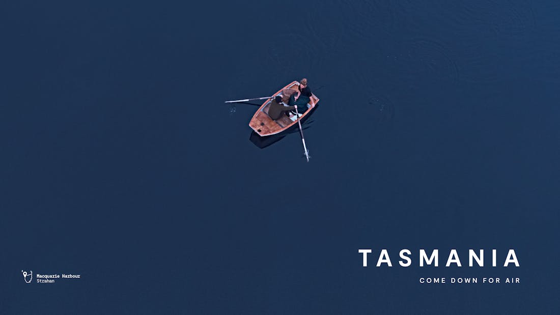 An image taken from above of two people in a row boat on a lake. Tasmania, come down for air.