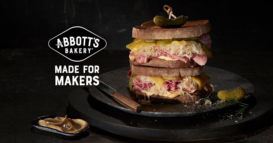 An advertisement for Abbott's Bakery showcasing an appetising image of a toasted ham sandwich on a black plate. A headline reads: "Made for makers".