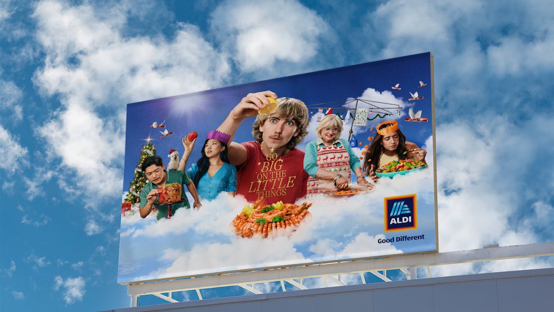 An image of a billboard. 5 people are standing in the sky on a cloud, admiring food related to Christmas. The ALDI logo and the words "Go Big On The Little Things" are overlaid on the image. 