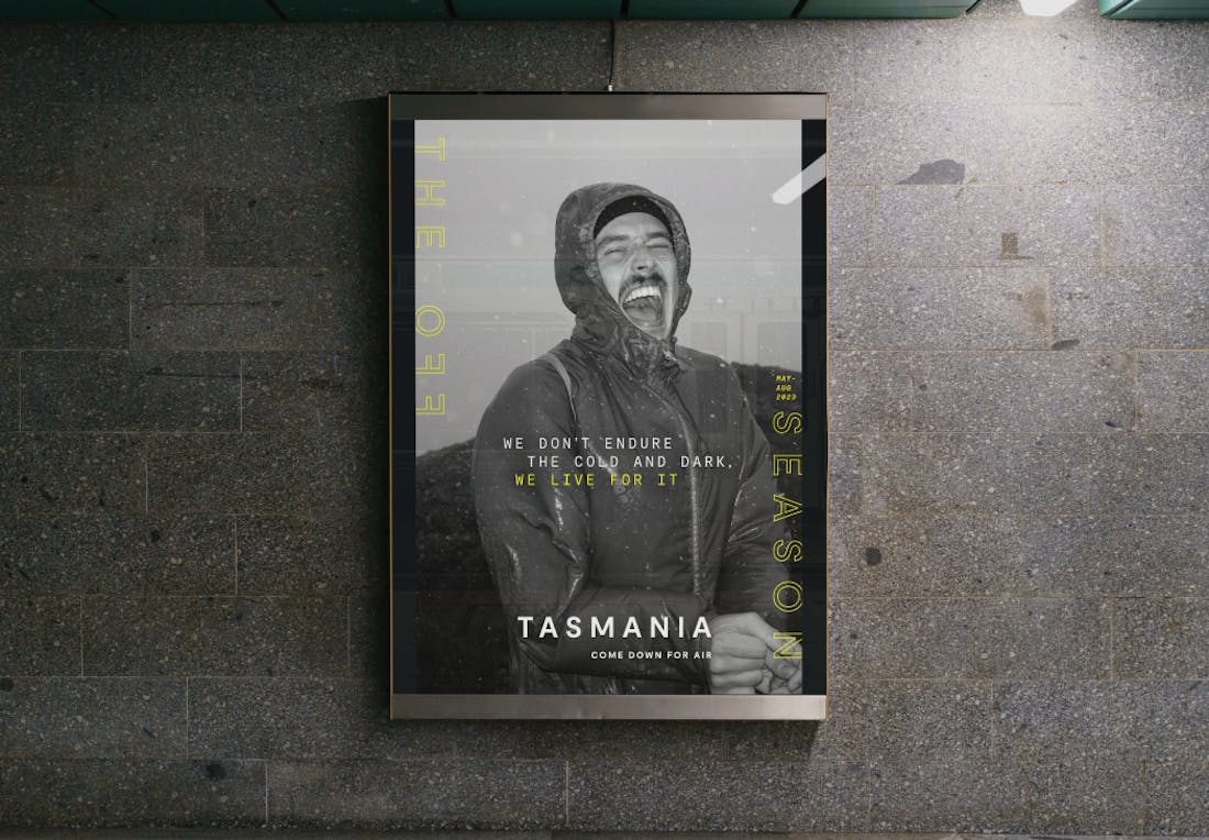 A billboard ad for Tourism Tasmania featuring a black and white image of a man with a joyful expression. The tagline reads: "The off season".